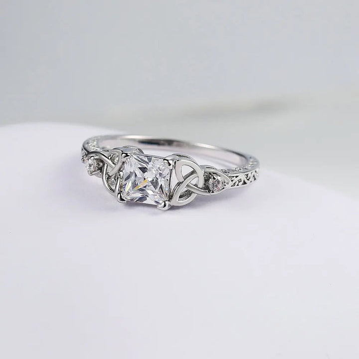 Anillo con diseño de nudo y piedra preciosa plateada en el centro